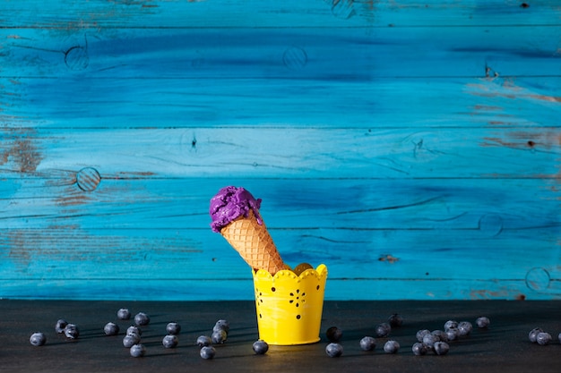 Delicioso cono de helado de arándanos en la vieja pared azul de madera