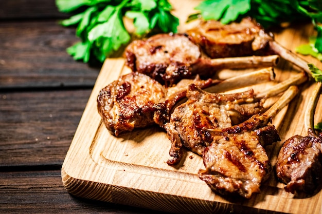 Delicioso costillar de cordero a la parrilla sobre una tabla para cortar con perejil