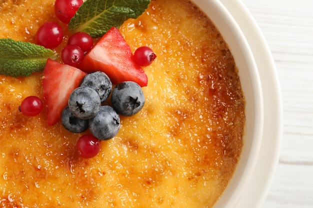 Delicioso creme brulee com frutas frescas na mesa de madeira branca closeup