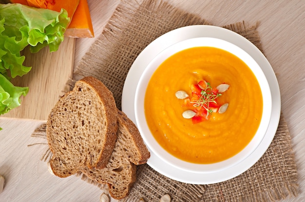 Delicioso creme de sopa de abóbora em uma tigela na mesa de madeira