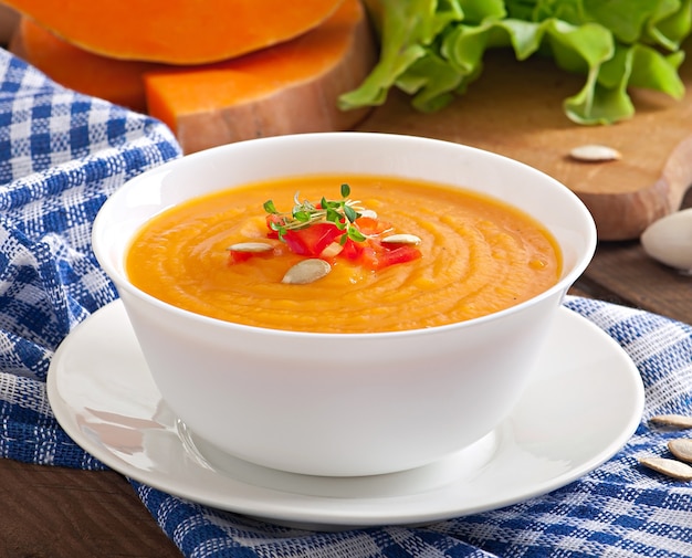 Delicioso creme de sopa de abóbora em uma tigela na mesa de madeira