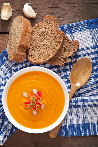 Delicioso creme de sopa de abóbora em uma tigela na mesa de madeira