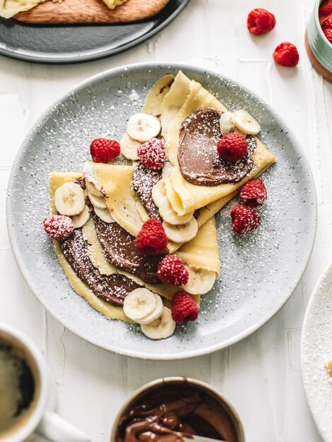 Foto delicioso crepe con frambuesa y plátano y chocolate