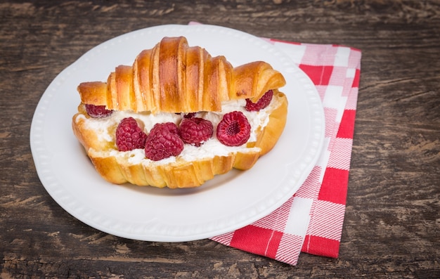 Delicioso croissant com creme e framboesas. Para o café da manhã.