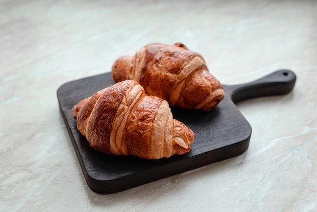 Delicioso croissant crocante com chocolate com uma xícara de café revigorante em um fundo claro de concreto Delicioso café da manhã nutritivo