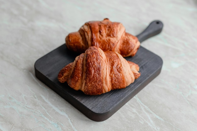 Delicioso croissant crocante com chocolate com uma xícara de café revigorante em um fundo claro de concreto Delicioso café da manhã nutritivo