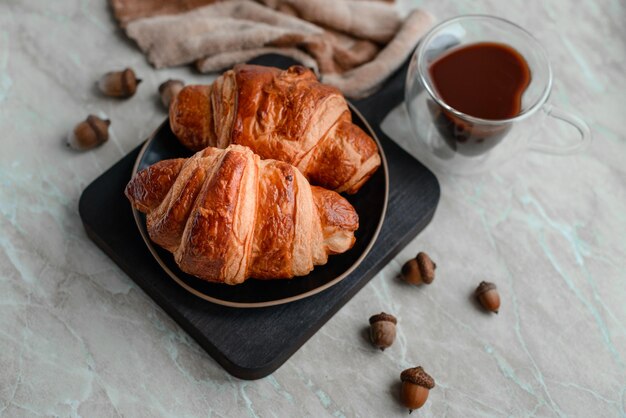 Delicioso croissant crocante com chocolate com uma xícara de café revigorante em um fundo claro de concreto Delicioso café da manhã nutritivo