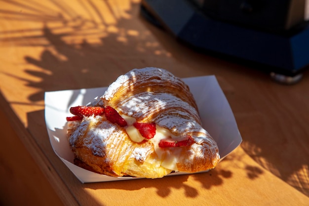 Delicioso croissant crocante recheado com creme e decorado com morangos. Café da manhã.