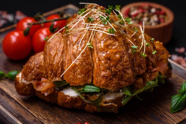 Delicioso croissant crujiente con salmón, lechuga, queso y tomates