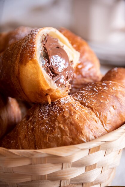 Delicioso croissant dulce con chocolate sobre mesa de madera blanca