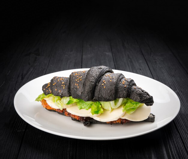 Delicioso croissant negro con relleno sobre fondo rústico de madera negro