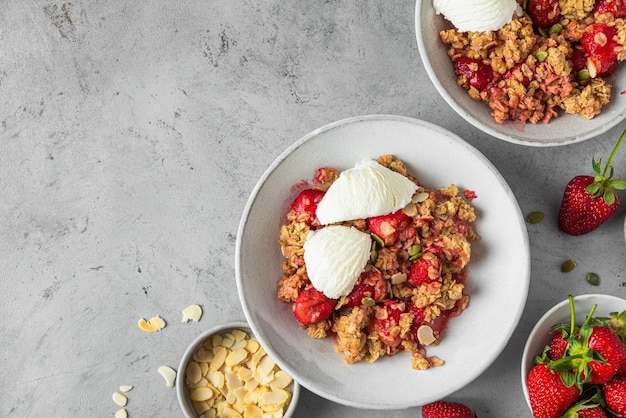 Delicioso crumble de morango com sorvete de amêndoas e sementes de abóbora em um prato no fundo cinza Vista superior