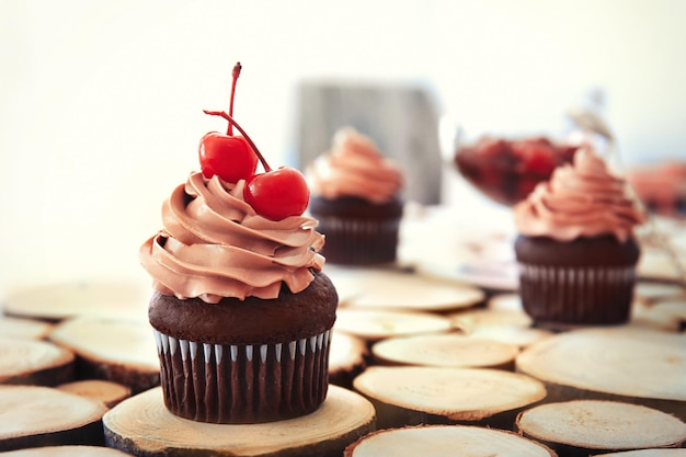 Delicioso cupcake de chocolate con cerezas sobre fondo claro