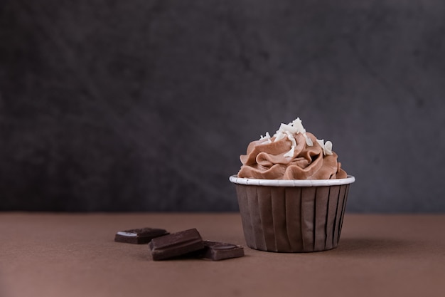 Delicioso cupcake de chocolate con crema sobre un fondo oscuro Dulces para una fiesta