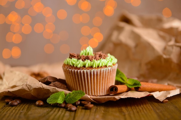 Delicioso cupcake con crema de mantequilla en la mesa de madera sobre fondo de luces