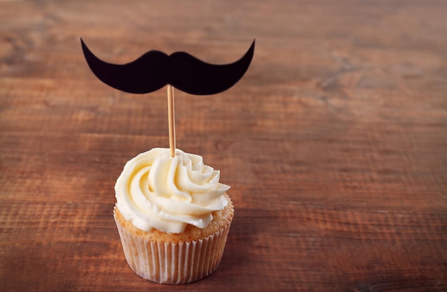 Delicioso cupcake criativo com bigode na mesa de madeira
