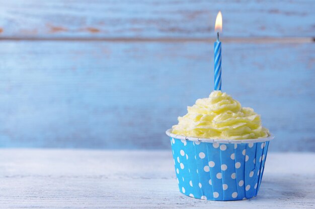 Delicioso cupcake de cumpleaños en la mesa sobre fondo de madera