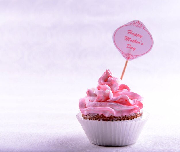 Foto delicioso cupcake con inscripción en la mesa sobre fondo beige