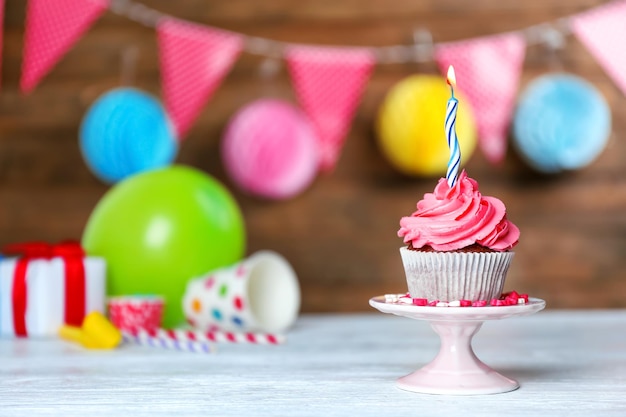 Foto delicioso cupcake con vela encendida sobre fondo festivo