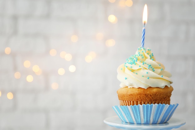 Delicioso cupcake con vela sobre fondo borroso