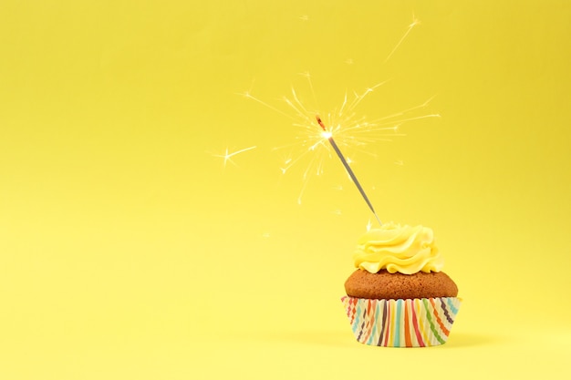 Delicioso cupcake con una vela sobre un fondo de color con espacio para texto