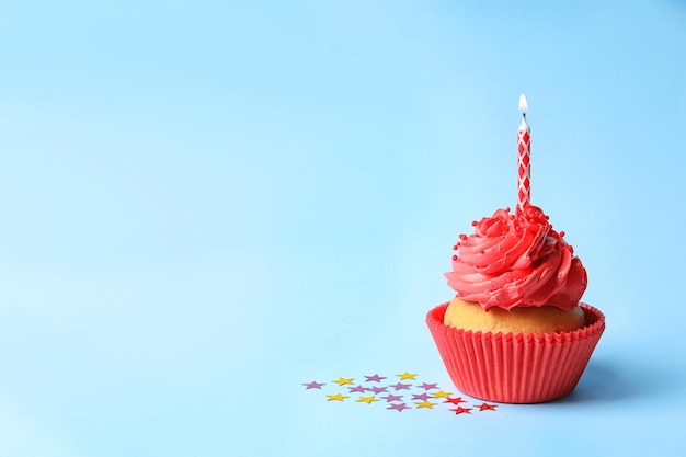 Delicioso cupcake con vela sobre fondo de color