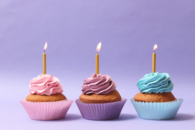 Delicioso cupcake con una vela sobre un fondo de color