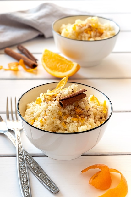 Delicioso cuscús casero con naranjas y canela sobre fondo de madera rústica. Sabrosa comida vegana.