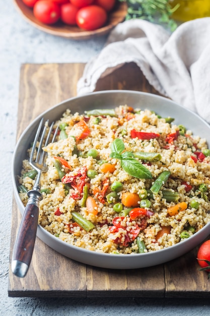 Delicioso cuscuz vegetariano caseiro com tomate, cenoura, feijão verde, pimentão e manjericão fresco