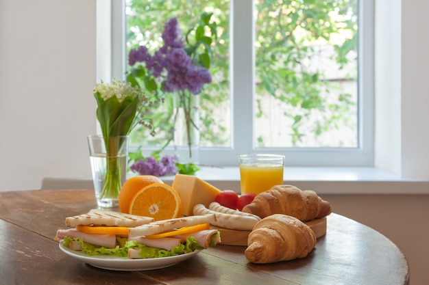 Delicioso desayuno con croissants, sándwiches y jugo de naranja.