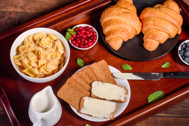 Delicioso desayuno con cruasanes recién hechos y bayas maduras en una hermosa mesa de madera