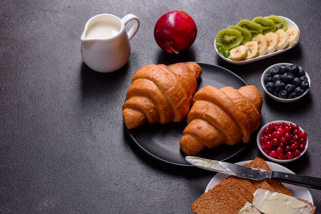 Delicioso desayuno con cruasanes recién hechos y bayas maduras en una hermosa mesa de madera