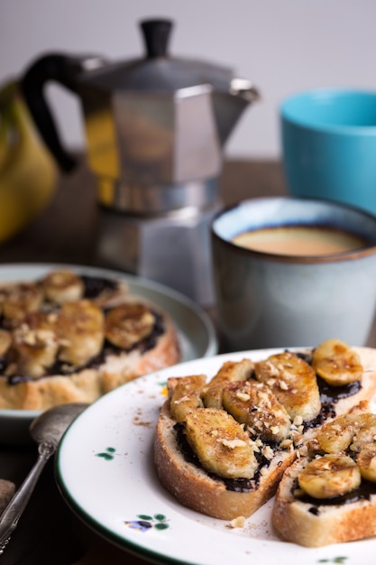 Delicioso desayuno francés - tostadas con chocolate y plátanos fritos sobre fondo de madera