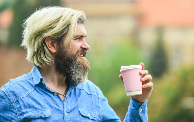 Delicioso desayuno hombre barbudo bebiendo café mientras camina al aire libre chico hipster barbudo con ropa informal disfruta relajándose el fin de semana bebiendo por la mañana estudiante de concepto en descanso para tomar café