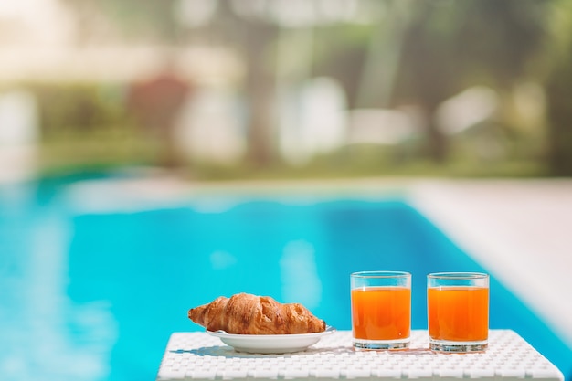 Delicioso desayuno limón, café, croissant junto a la piscina.