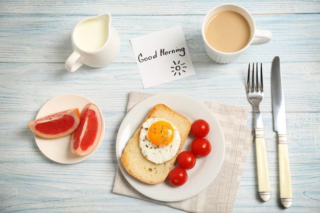 Delicioso desayuno y nota de saludo de BUENOS DÍAS en la vista superior de la mesa de madera