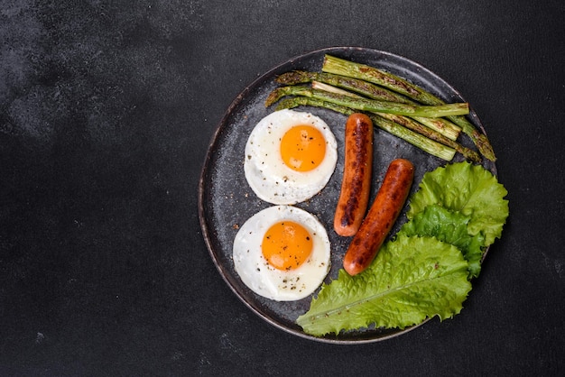 Un delicioso desayuno nutritivo con huevos fritos, salchichas, espárragos, tomates, aguacate, especias y hierbas.