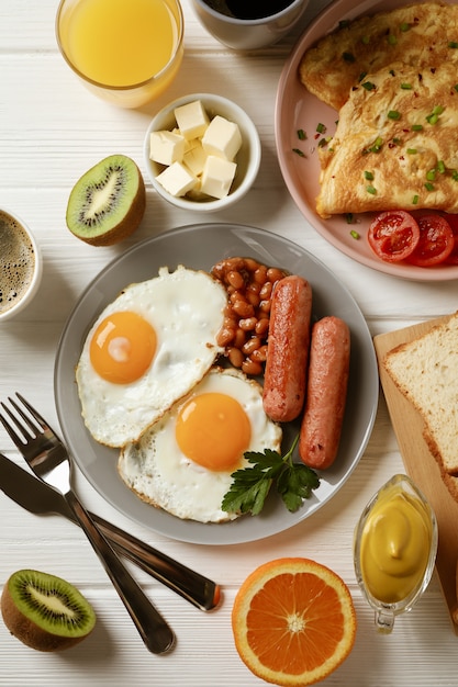 Delicioso desayuno o almuerzo con huevos fritos en la superficie de madera blanca, vista superior