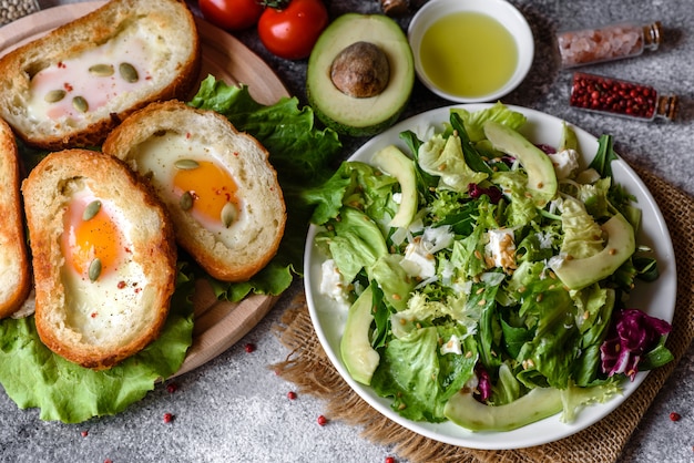 Delicioso desayuno con roncos, huevos, aguacate y tomates cherry. Agradable comida de la mañana con sándwiches frescos