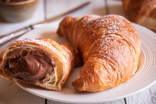 Delicioso doce croissant com chocolate na mesa de madeira branca