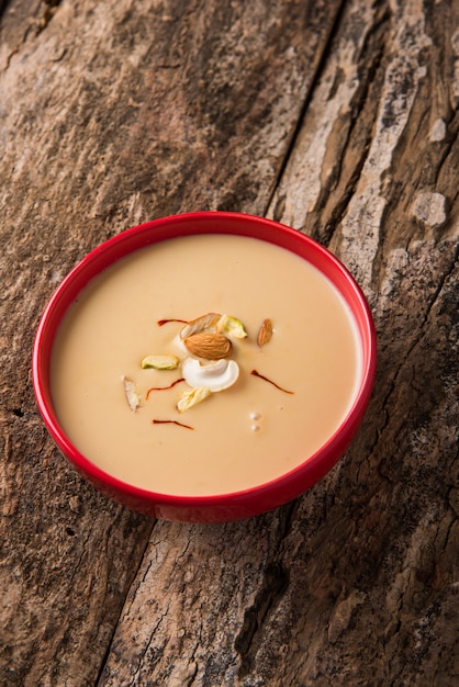 Foto delicioso doce indiano rabdi ou rabri com coberturas de frutas secas. a comida de festival popular testa muito bem com jalebi / jilbi. servido em uma tigela sobre mesa colorida ou de madeira. foco seletivo