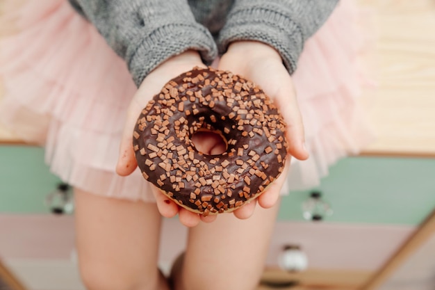 Delicioso donut de chocolate glaseado en las manos Vista desde arriba