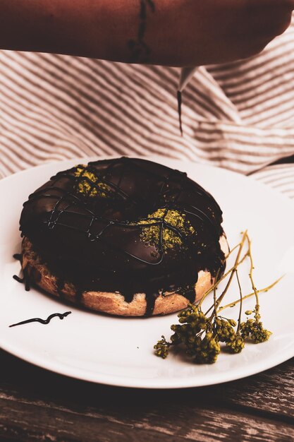 Delicioso donut com calda de chocolate e pedaços de pistache