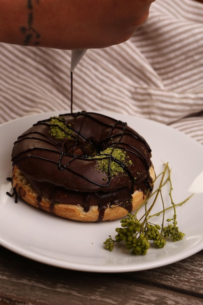 Delicioso donut com calda de chocolate e pedaços de pistache