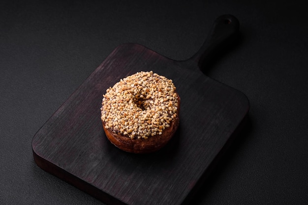 Delicioso donut com recheio de creme e nozes em um fundo escuro de concreto