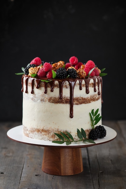 Foto delicioso e lindo bolo artesanal. confeitaria para o feriado. sobremesa decorada com frutas frescas, folhas verdes e doces.