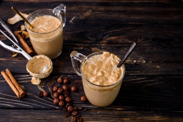 Delicioso e perfumado dalgona café em copos de vidro, paus de canela, cogumelos secos, uma colher de café instantâneo, açúcar.