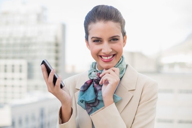 Delicioso empresária de cabelos castanha inteligente segurando um telefone móvel