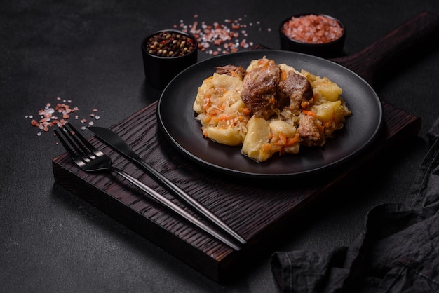 Delicioso ensopado de legumes com batatas de carne, cenouras e repolho em uma placa preta