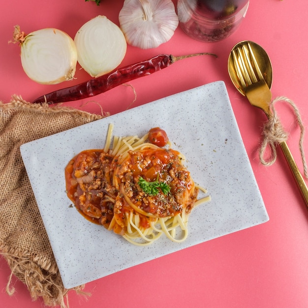 Foto delicioso espaguete com molho à bolonhesa servido em prato quadrado branco